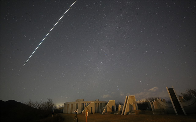 屋外モニュメントとふたご座流星群の流星の写真
