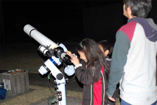 望遠鏡を操作する子の写真