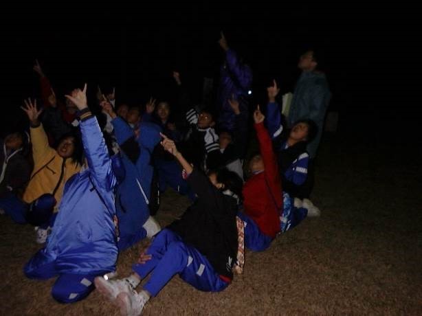 夜、屋外で星空を観察する子ども供たちの写真